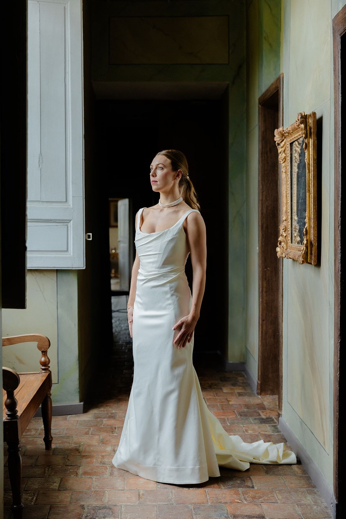 Bride pauses in a green marbled corridor framed by gilt picture frames