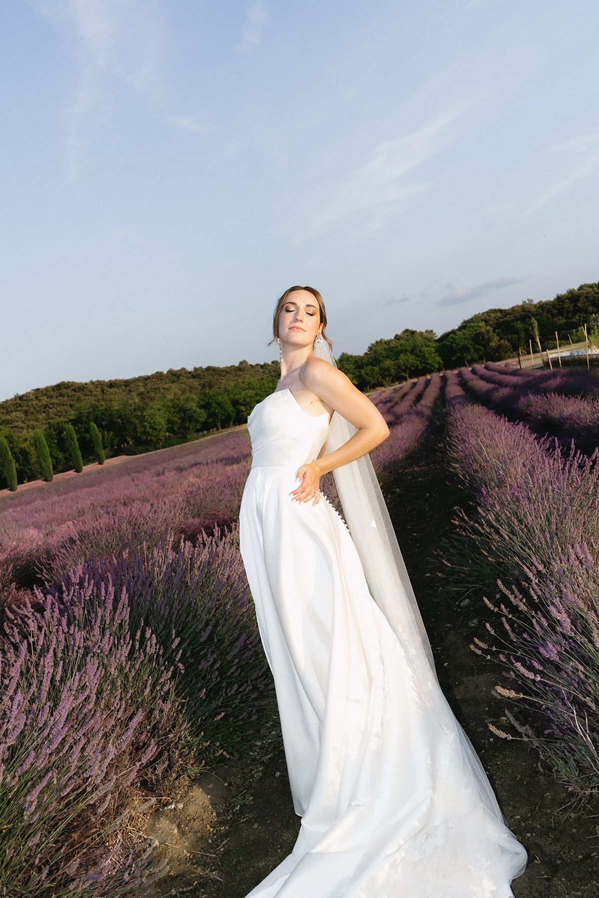 Bride in long veil standing in lavender field at Les Domaines de Patras, Provence