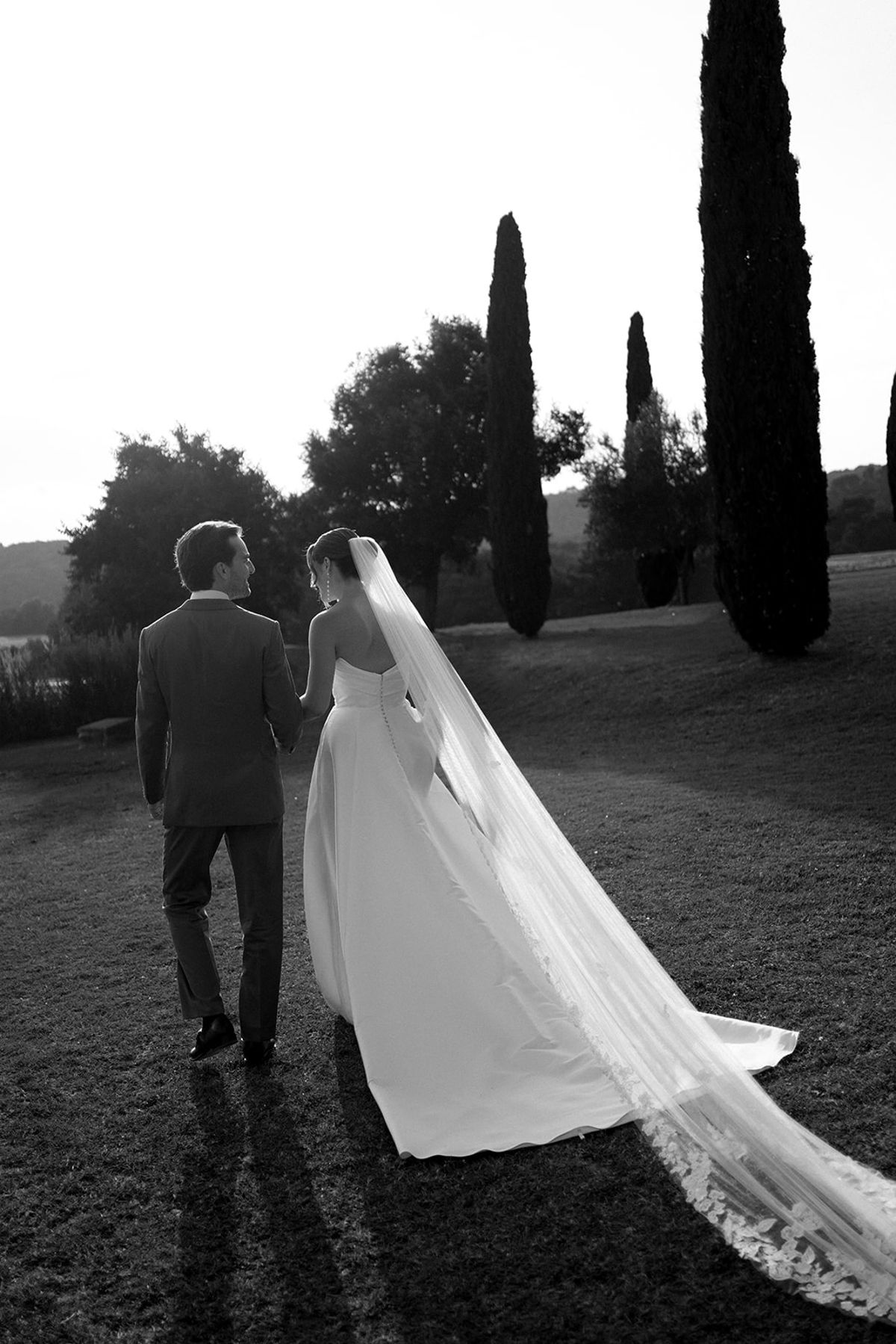 Couple walking with long cathedral veil in Provencal garden at Les Domaines de Patras, Provence