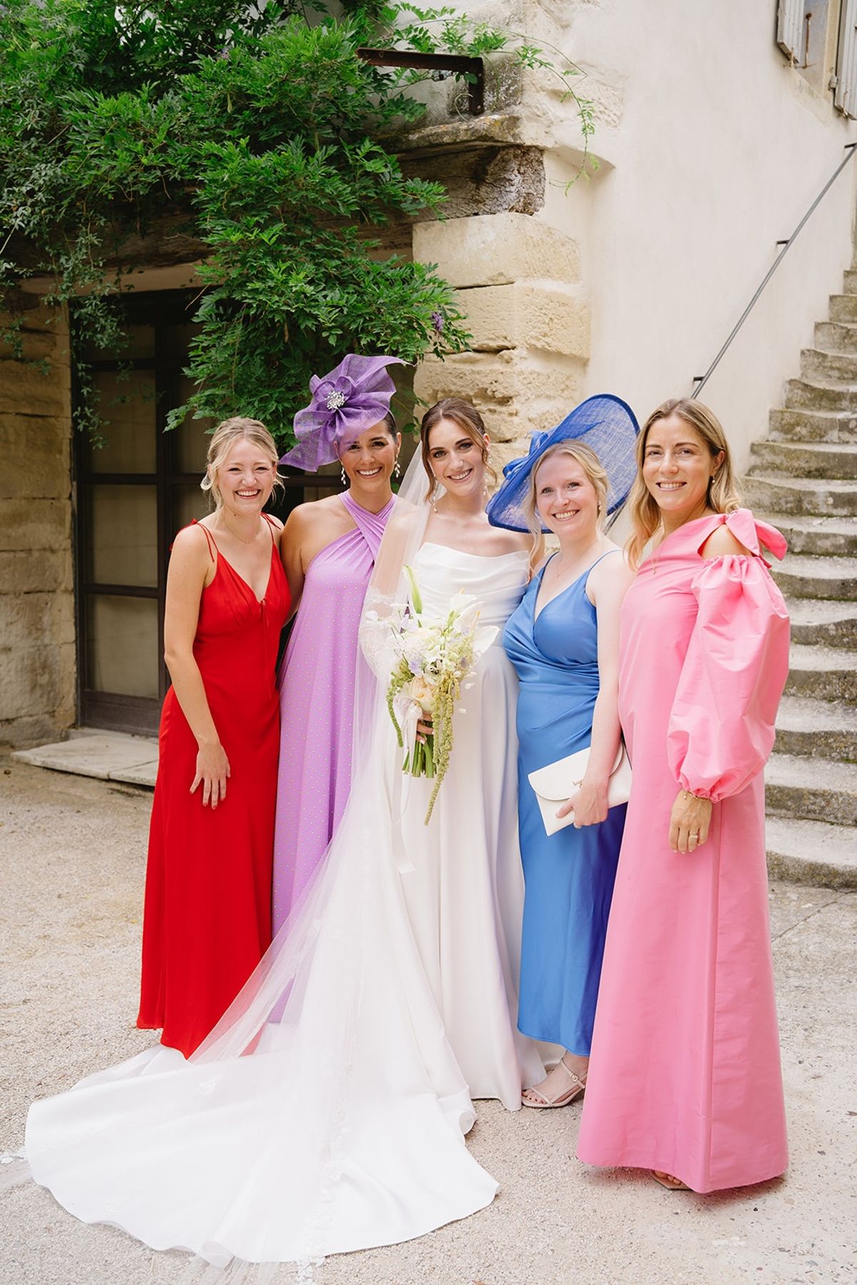 Bride with colourfully dressed wedding party in courtyard at Les Domaines de Patras, Provence