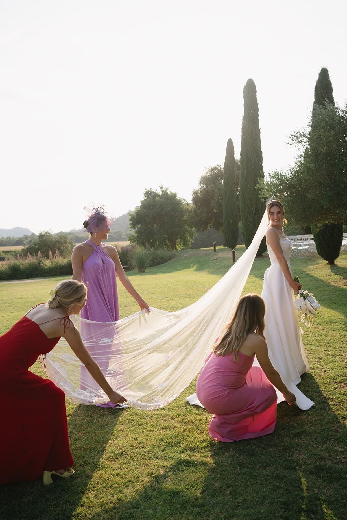 Friends arranging bride's long veil at golden hour at Les Domaines de Patras, Provence