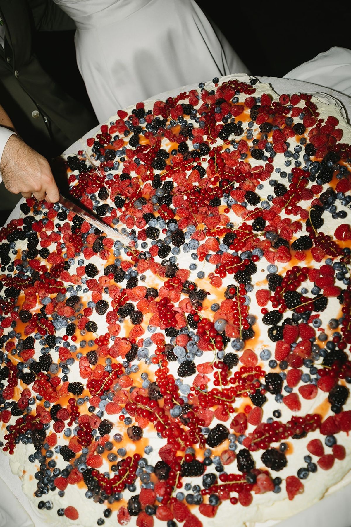 Couple cutting berry-topped wedding cake at Les Domaines de Patras, Provence