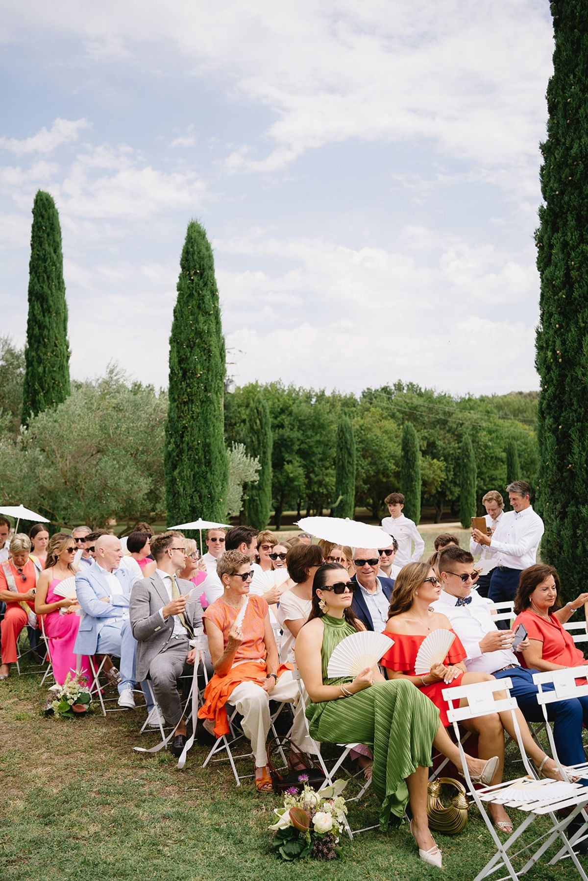 Ceremony guests with fans and parasols on lawn at Les Domaines de Patras, Provence