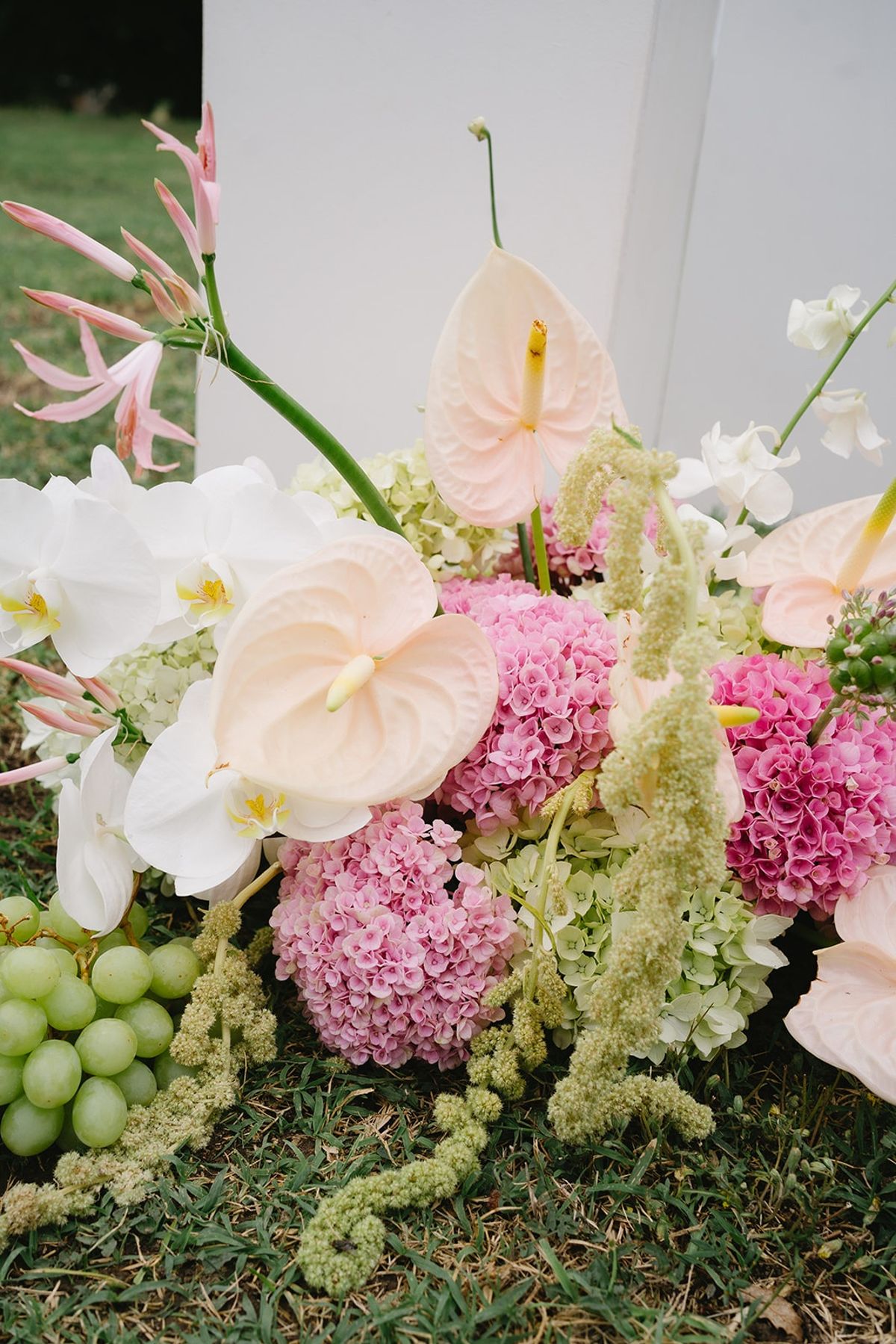 Pastel floral arrangement with grapes at altar base at Les Domaines de Patras, Provence