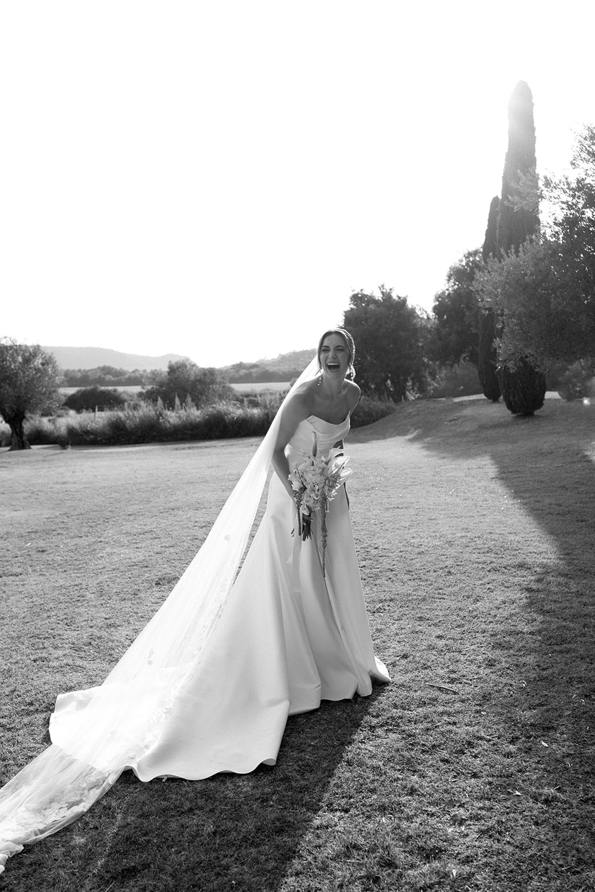 Laughing bride with long veil at golden hour at Les Domaines de Patras, Provence