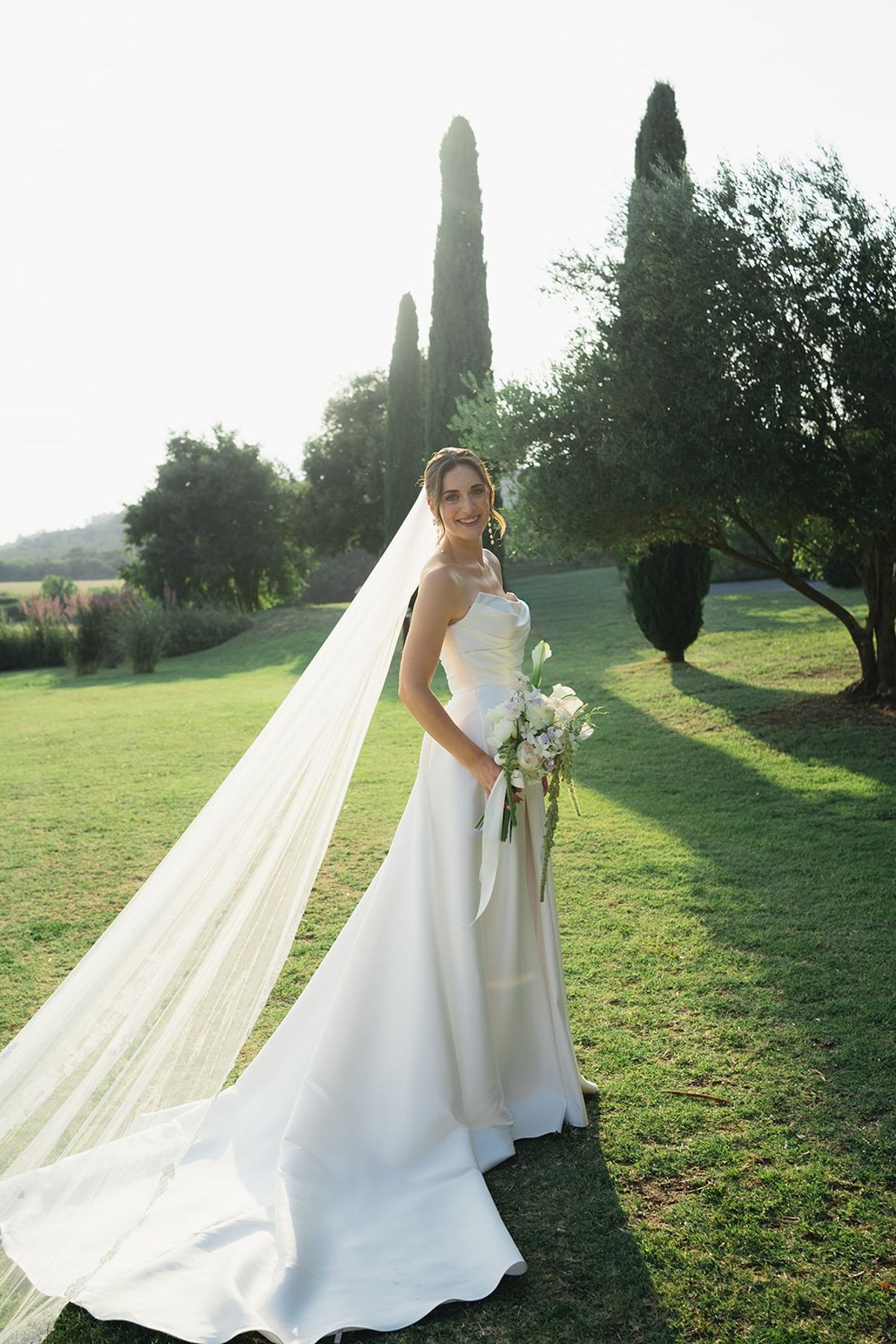 Bride with long veil and bouquet in golden light at Les Domaines de Patras, Provence