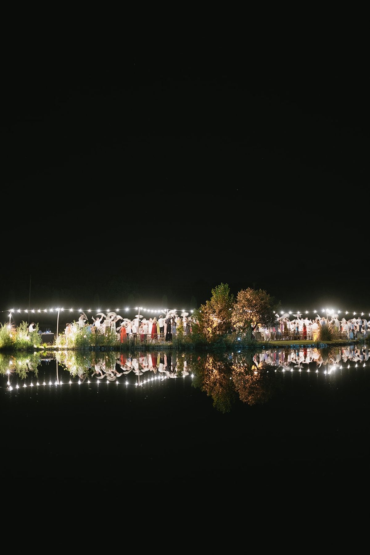 Night reception dinner reflected across lake at Les Domaines de Patras, Provence