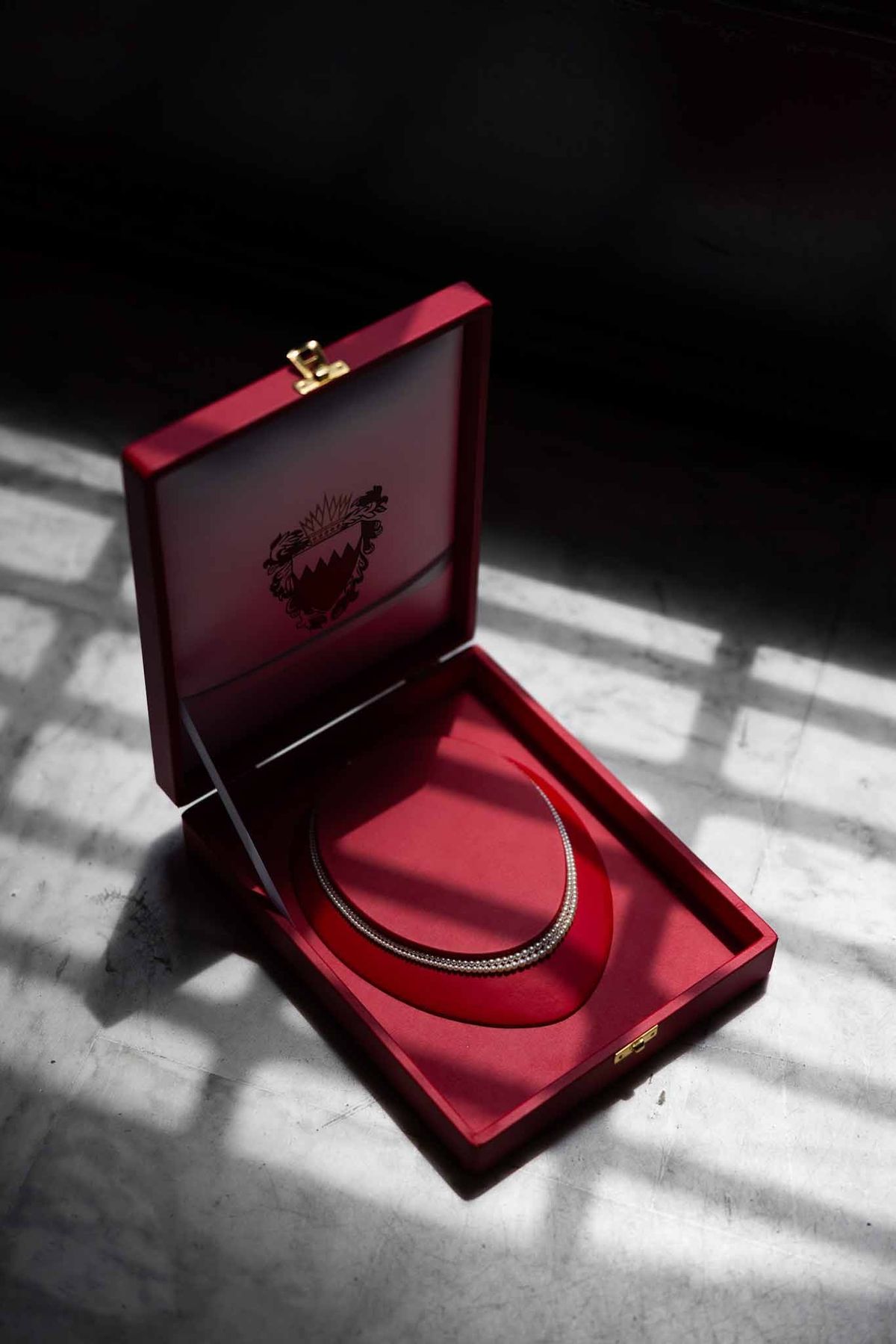 Diamond tennis necklace in red jewellery box with dramatic light at Parc Mougins