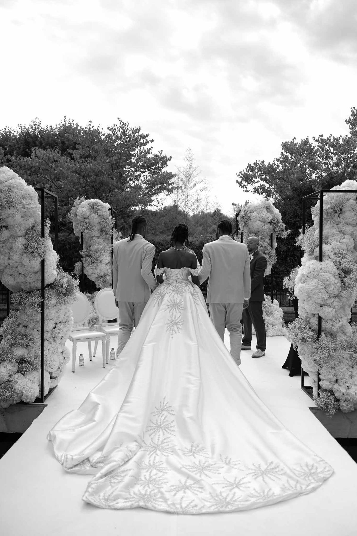 Bride walking down mirrored aisle with white hydrangea arrangements at Parc Mougins ceremony