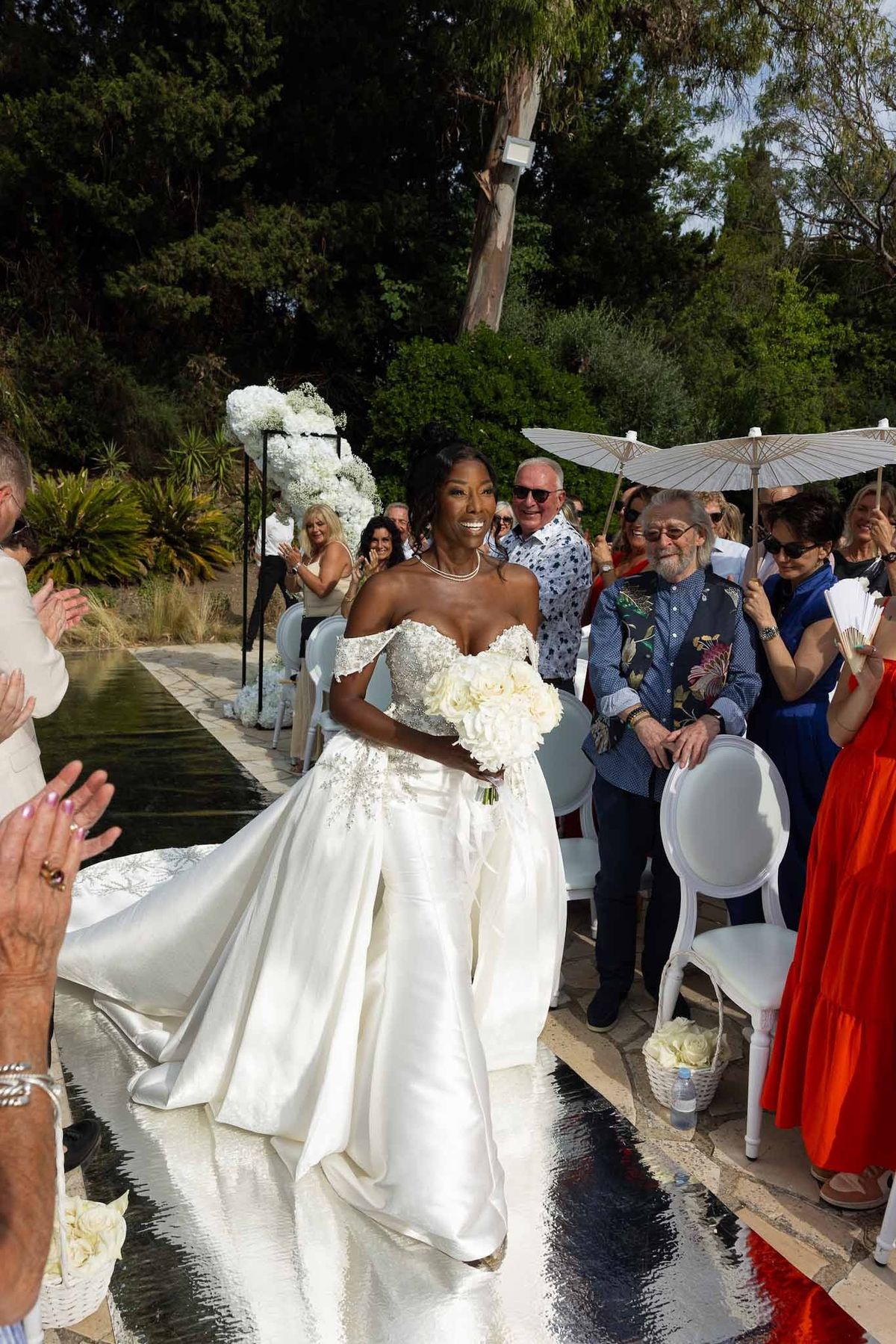 Bride walking down mirrored aisle with applauding guests at Parc Mougins ceremony