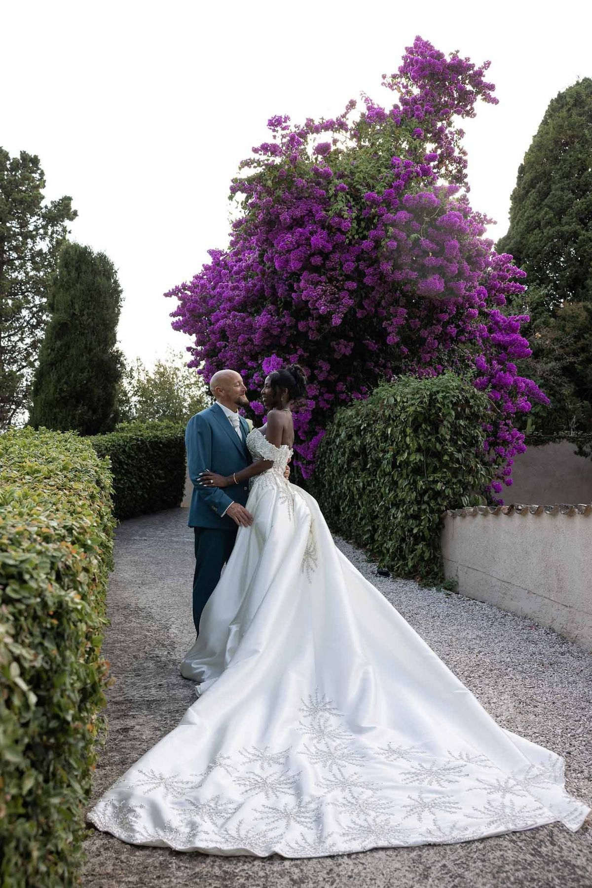 Couple embracing under purple bougainvillea tree in garden at Parc Mougins