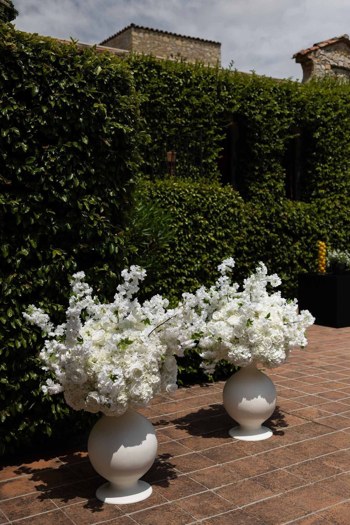 White ceramic urns with hydrangeas in garden pathway at Parc Mougins