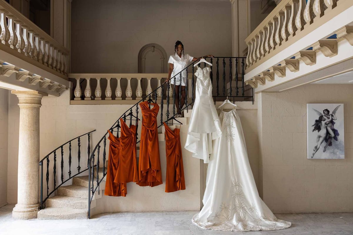 Bride on staircase with hanging wedding and bridesmaid dresses at Parc Mougins