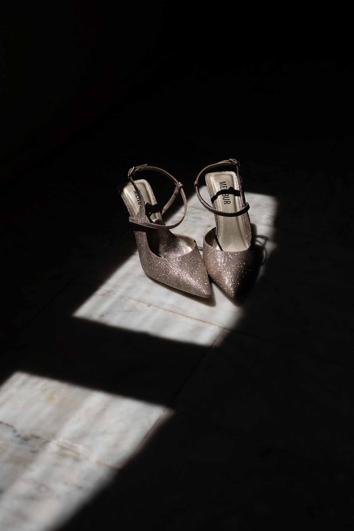 Silver sparkly bridal slingback heels in beam of light on marble floor at Parc Mougins