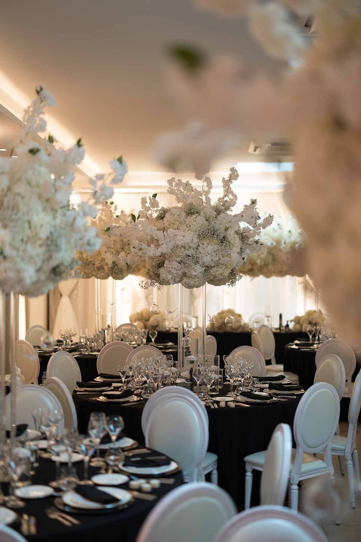Black and white reception tables with towering white floral centrepieces at Parc Mougins