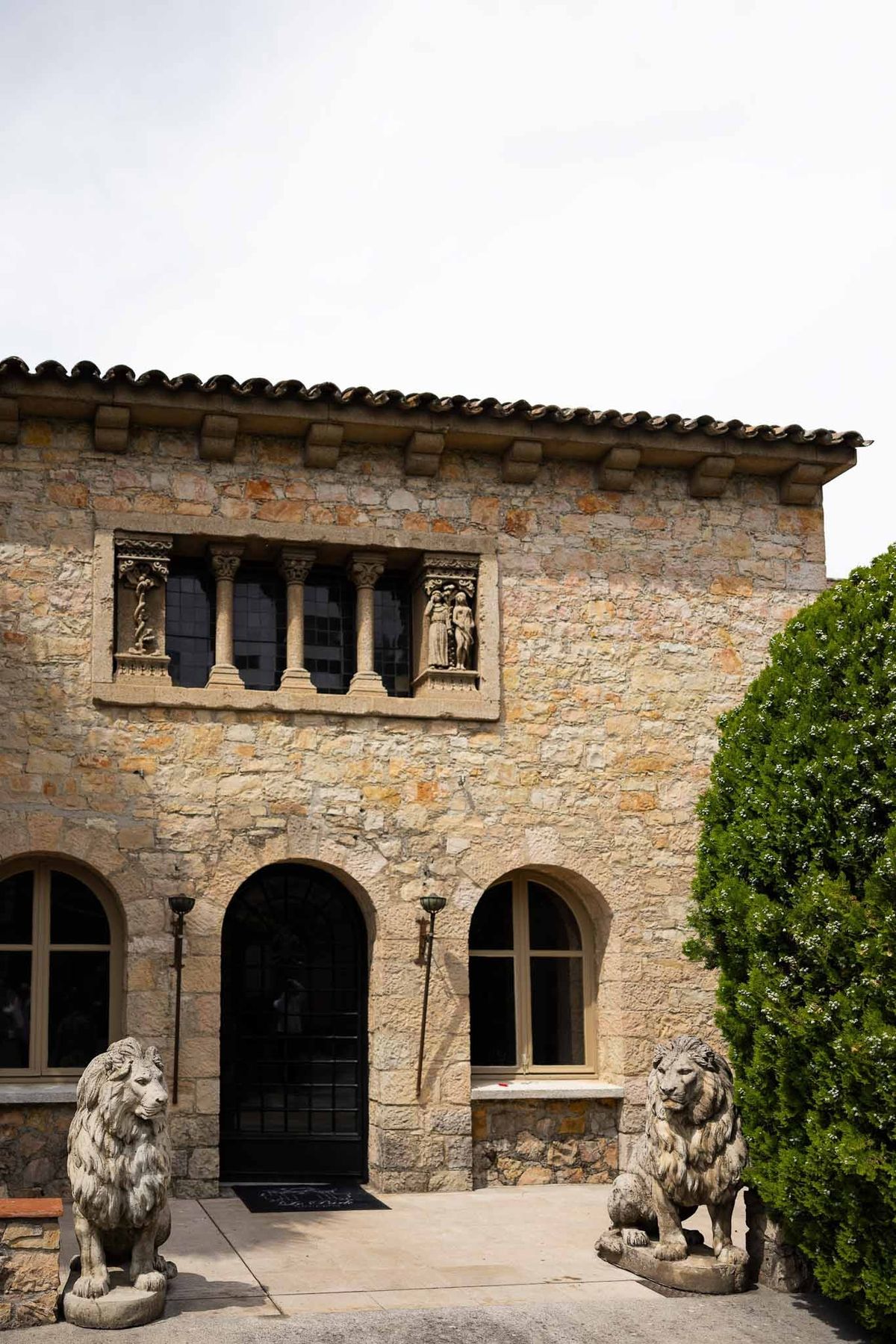 Medieval stone façade with arched doorways and lion statues at Parc Mougins