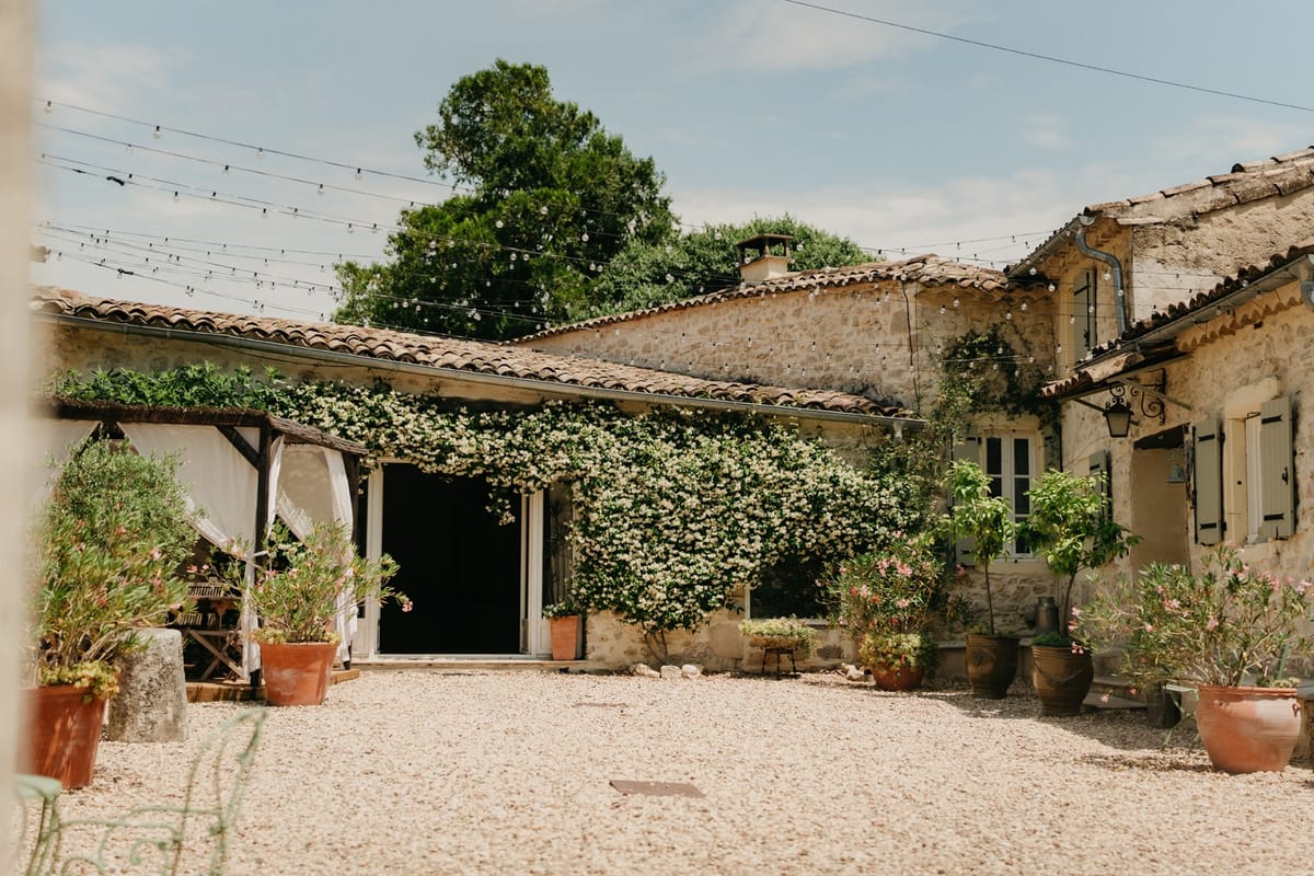 Stone courtyard with festoon lights, jasmine walls and terracotta pots in a French country mas.
