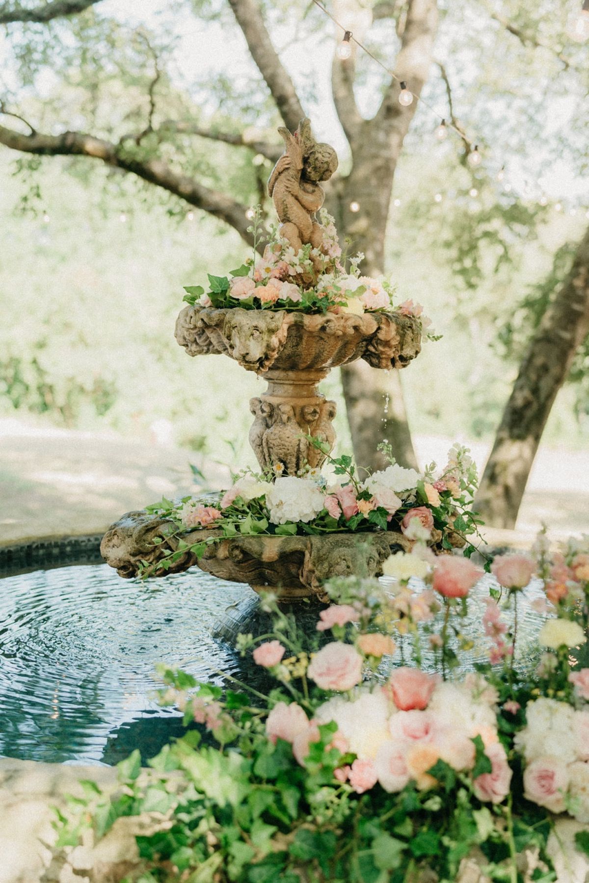 Detail of stone fountain altar with rose collar and ivy spilling over the pool rim.