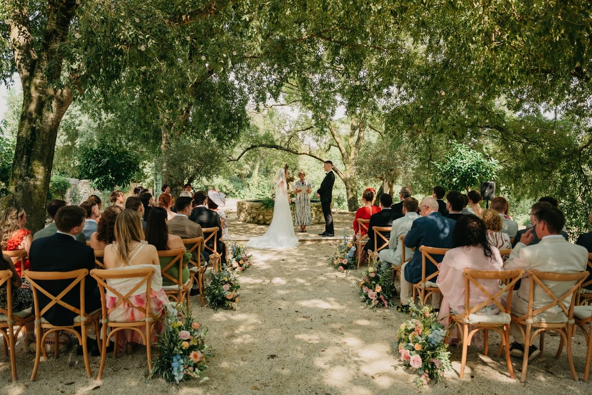 Wide view of outdoor ceremony with couple at fountain altar and seated guests on both aisles.