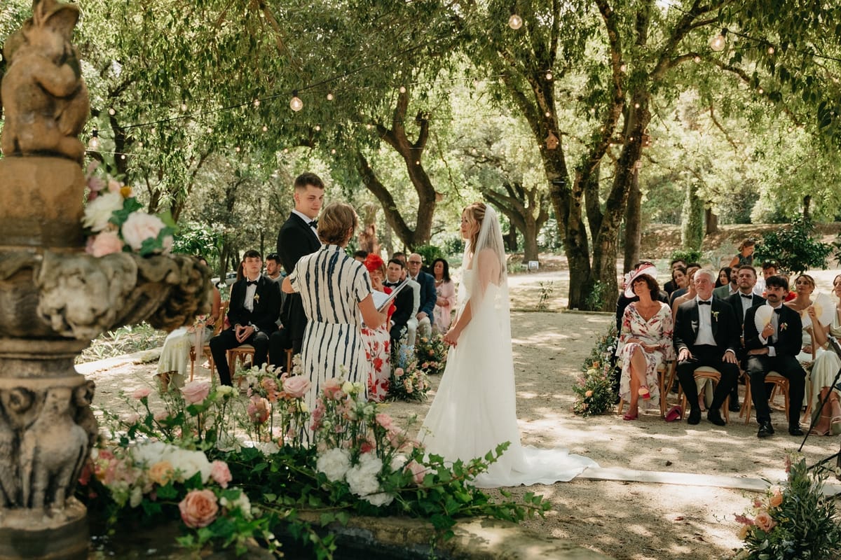 Family take part in ribbon handfasting ritual around couple at the floral fountain altar.