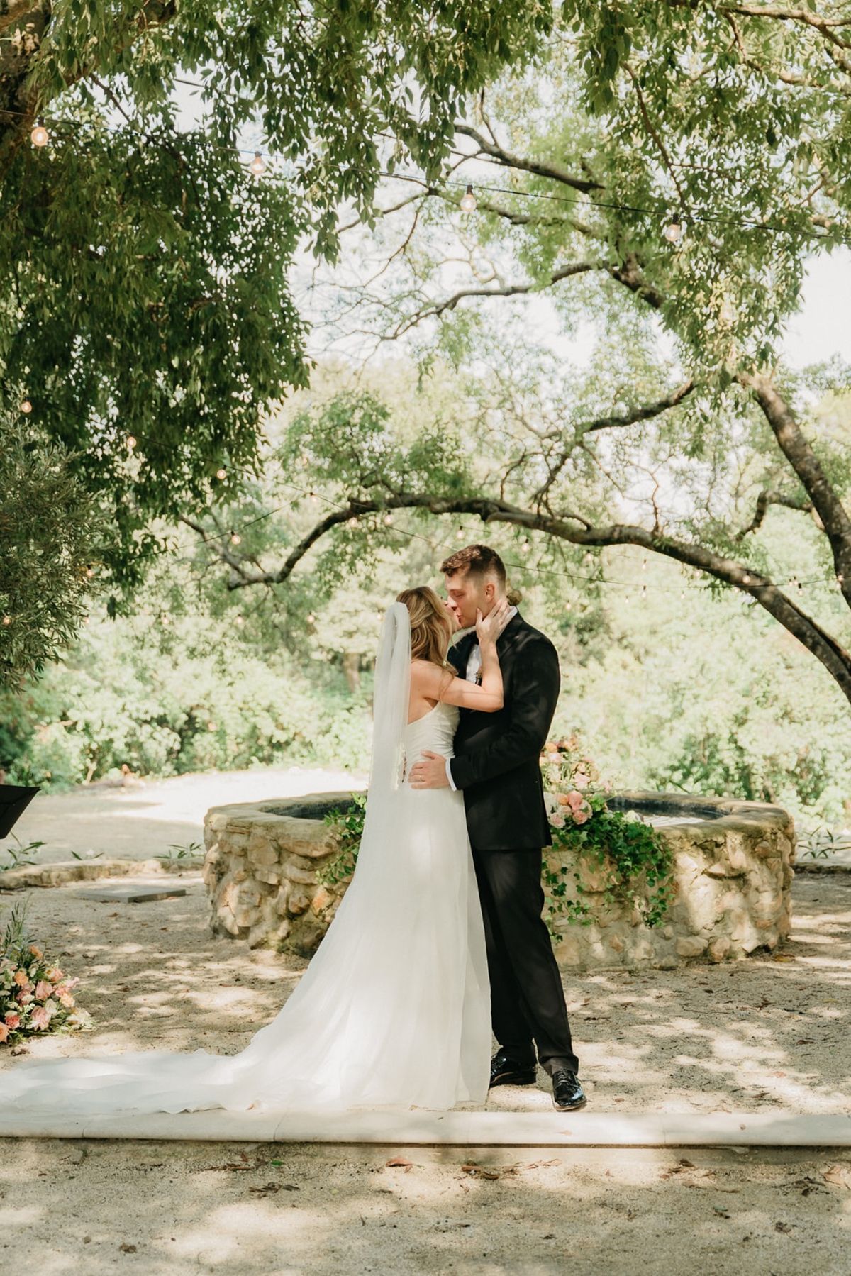 Couple share a quiet embrace at the stone fountain altar after the ceremony.
