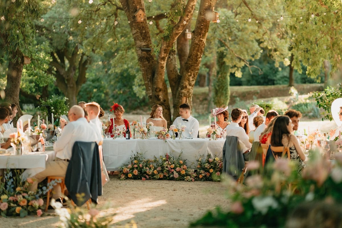 Wide reception view with seated couple at head table and meadow floral border across the front.