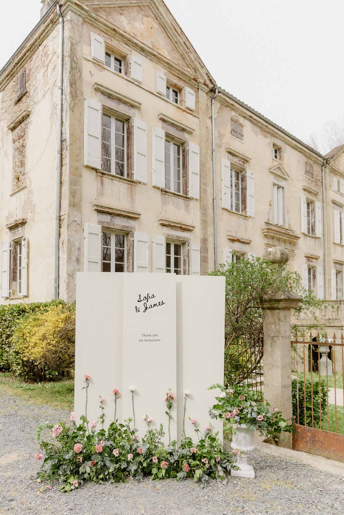 Wedding welcome sign reading Sofia and James with pink rose arrangement in front of French chateau