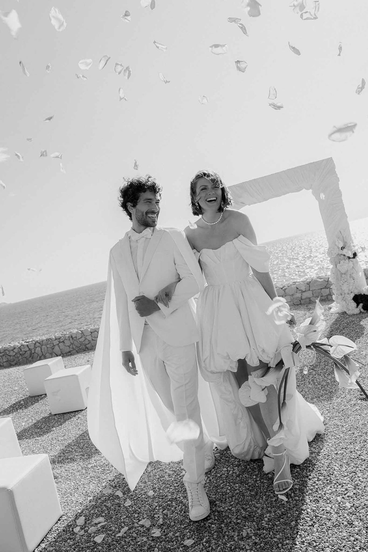 Black and white photo of wedding ceremony by the sea with white roses