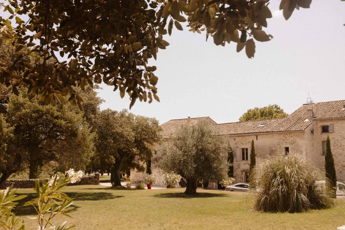 French stone mas with terracotta roofline, olive and cypress trees, ornamental grasses, and dry-stone wall border