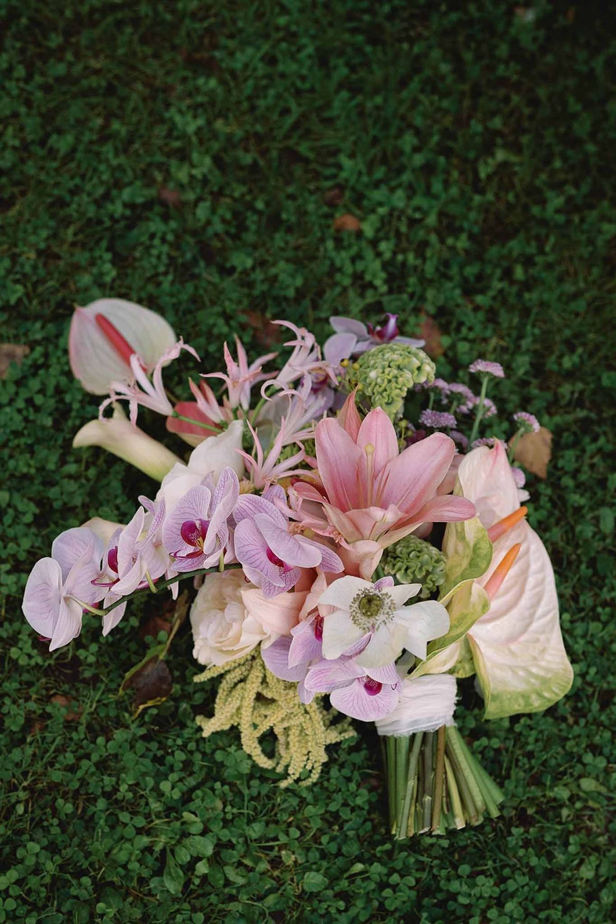 Pink orchid and anthurium bridal bouquet on lawn at Abbaye de Talloires