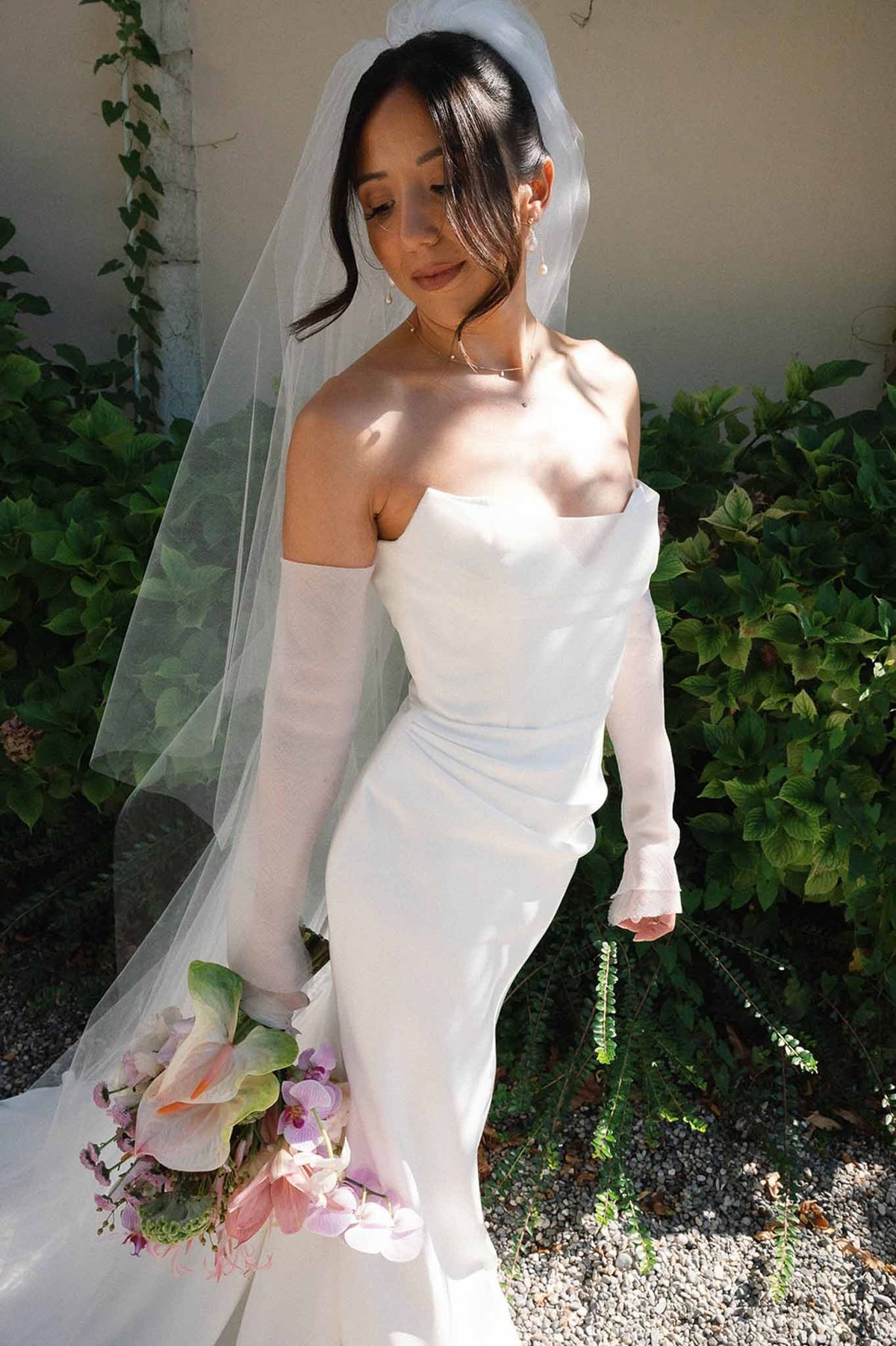Bride in mermaid gown with veil and gloves in garden at Abbaye de Talloires