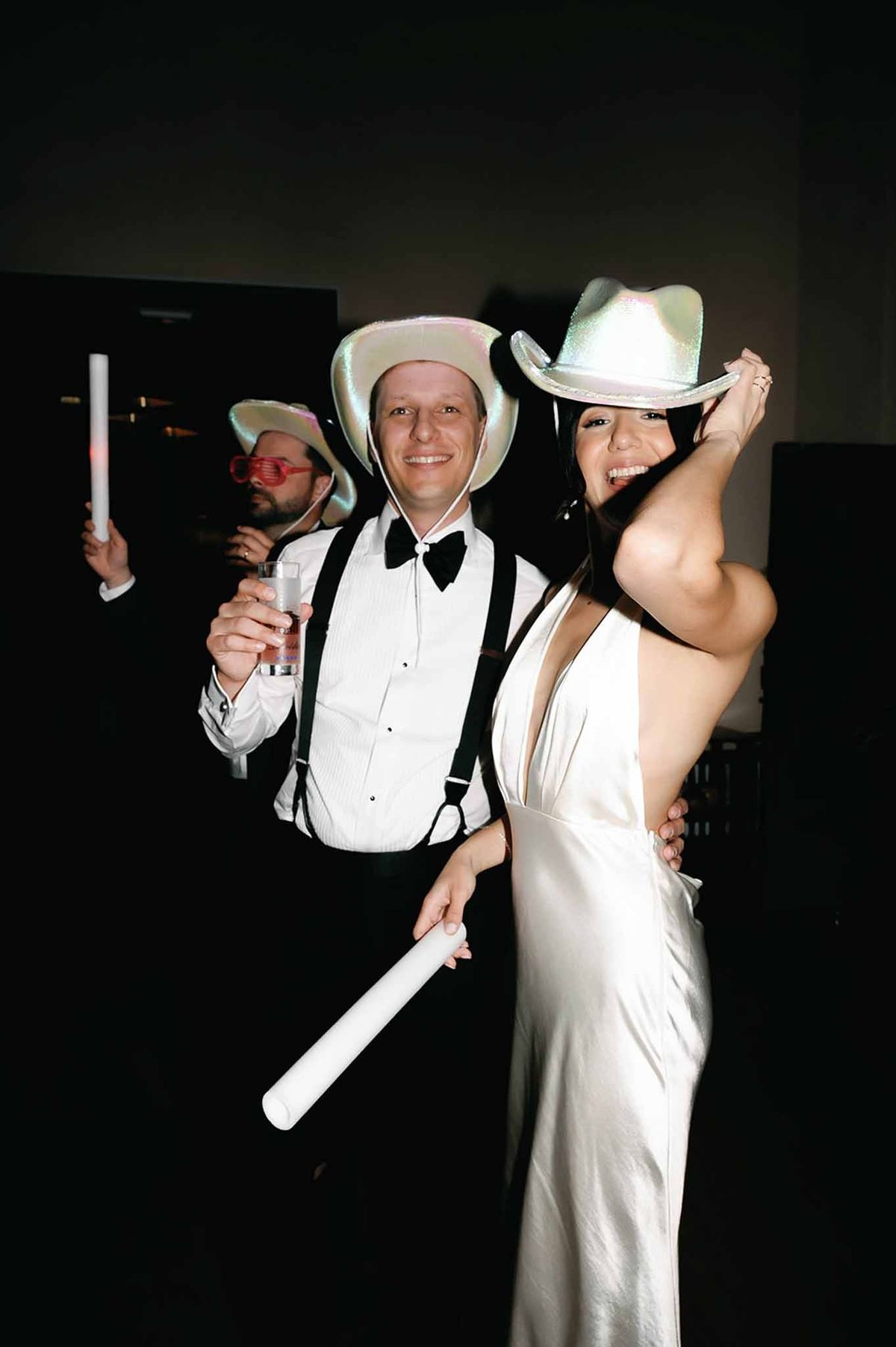 Couple posing with cowboy hats and glow sticks at after-party at Abbaye de Talloires