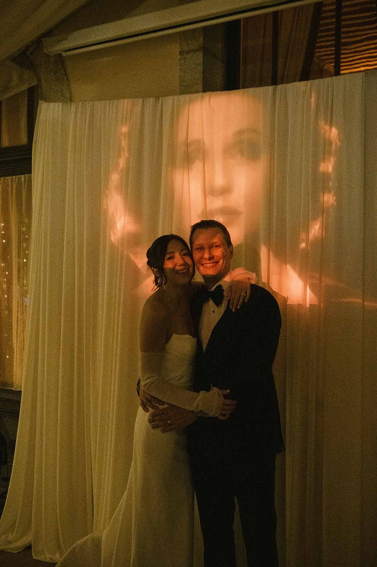 Couple embracing in front of projected image at reception at Abbaye de Talloires