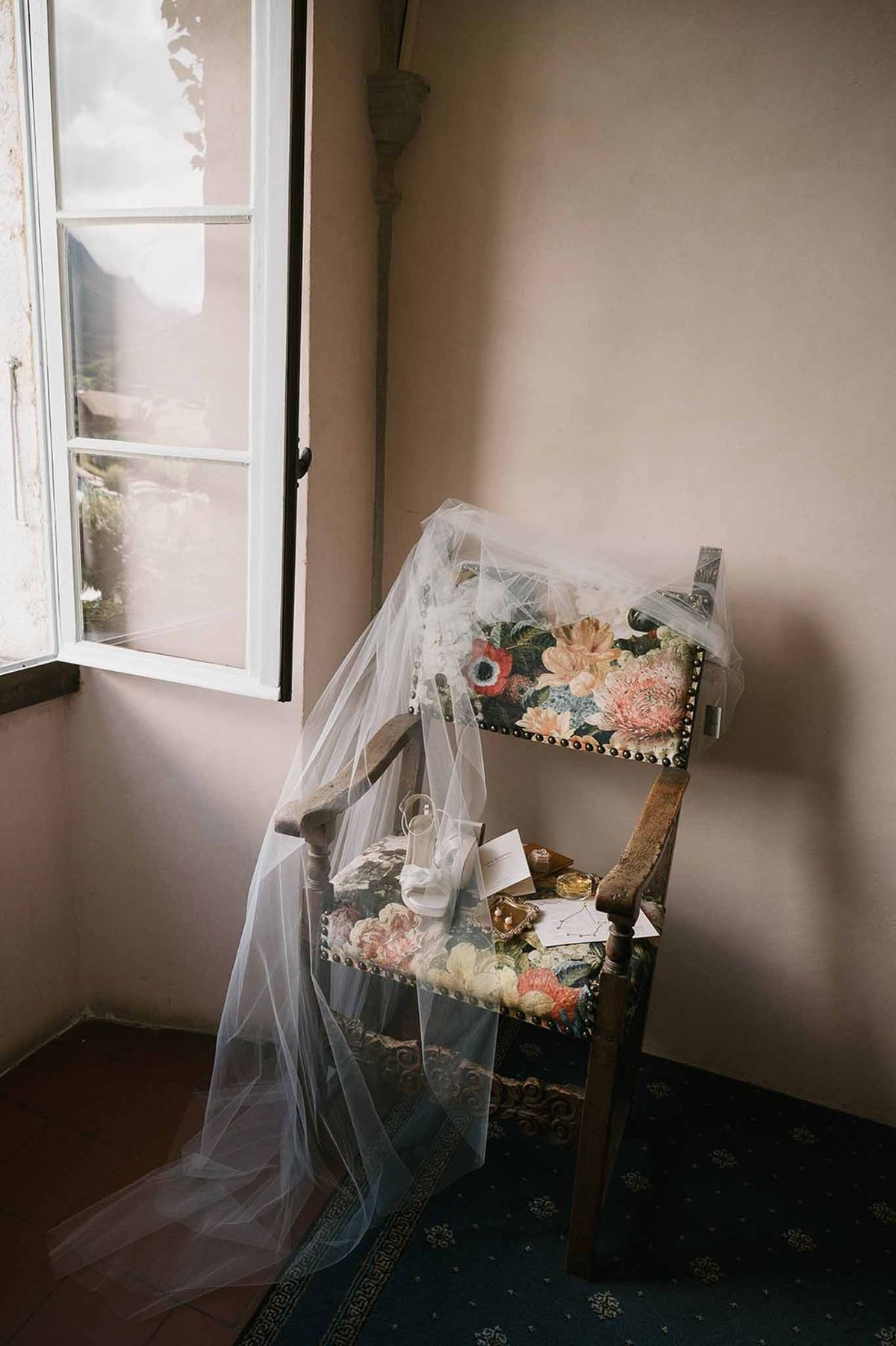 Bridal veil and accessories on vintage floral chair by window at Abbaye de Talloires