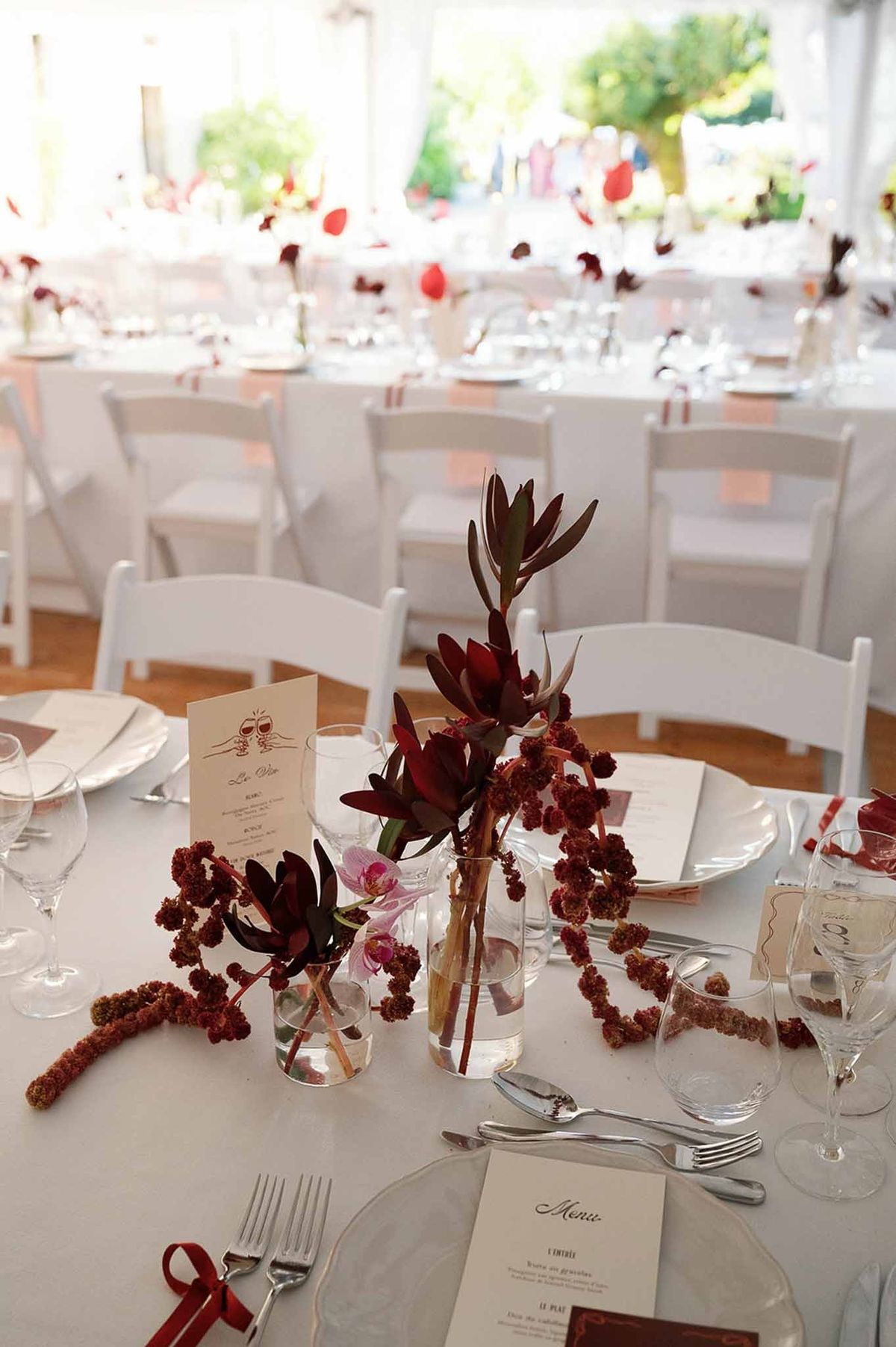 Burgundy floral reception table with menu cards under marquee at Abbaye de Talloires