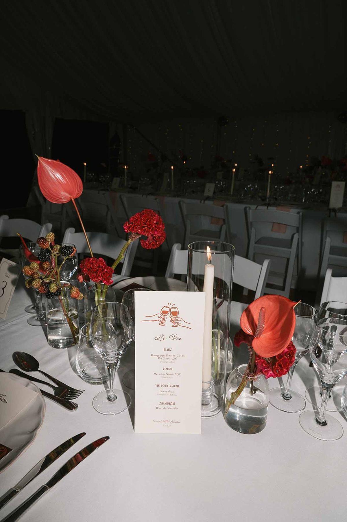 Evening reception table with candles and red floral centrepieces at Abbaye de Talloires