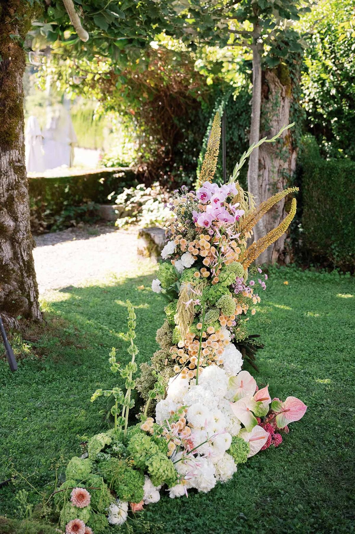Wild ceremony arch with hydrangeas, orchids and moss on garden lawn at Abbaye de Talloires