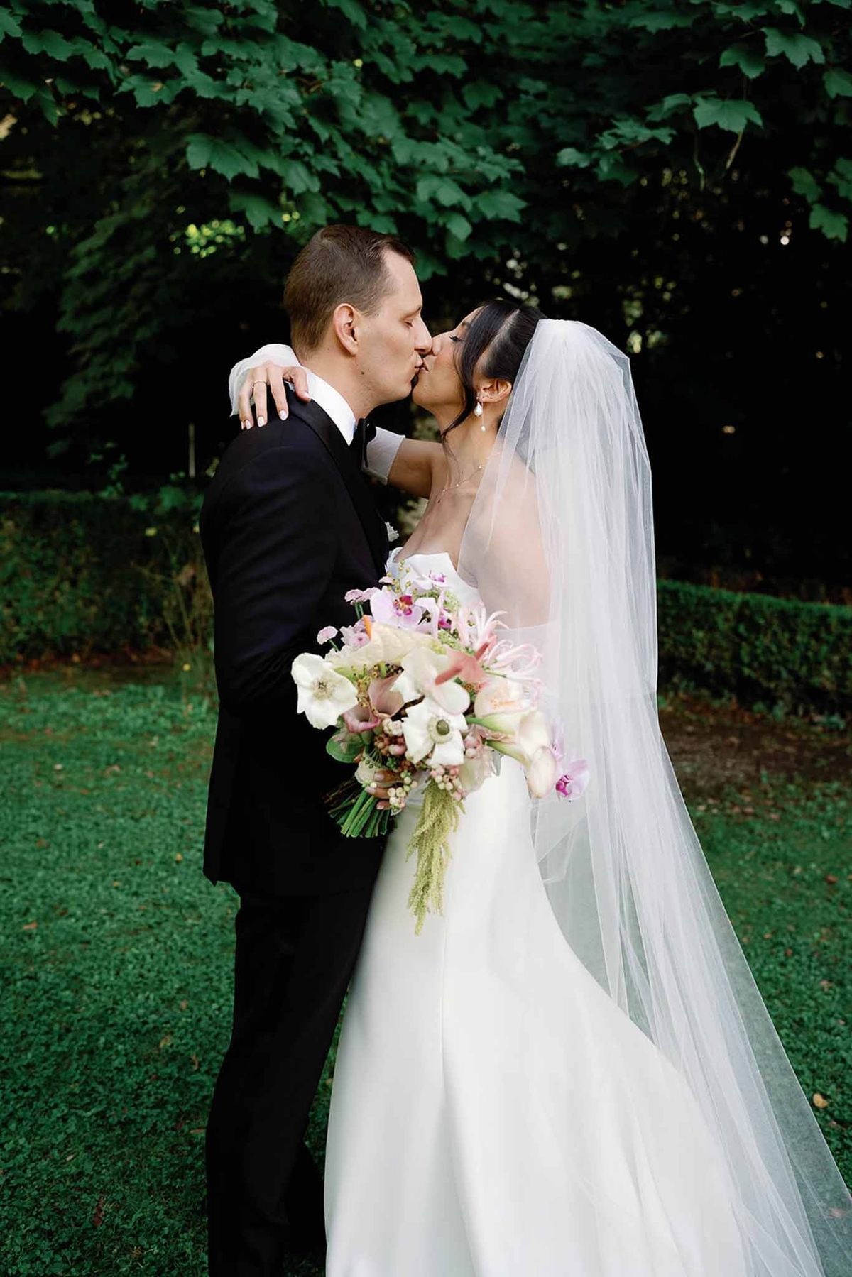 Couple kissing with bouquet in garden at Abbaye de Talloires