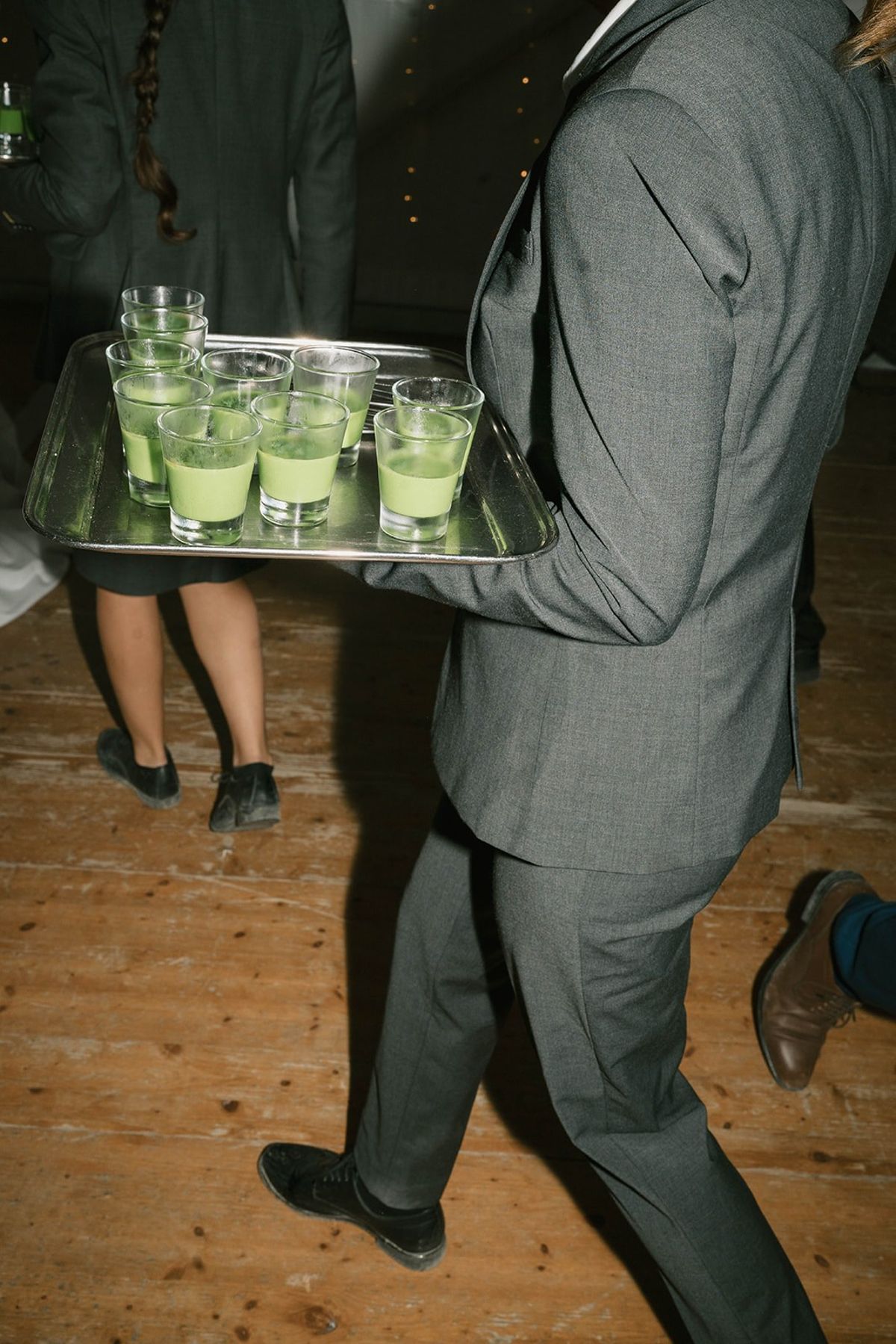 Reception waiter carrying a tray of green liqueur shots at Abbaye de Talloires