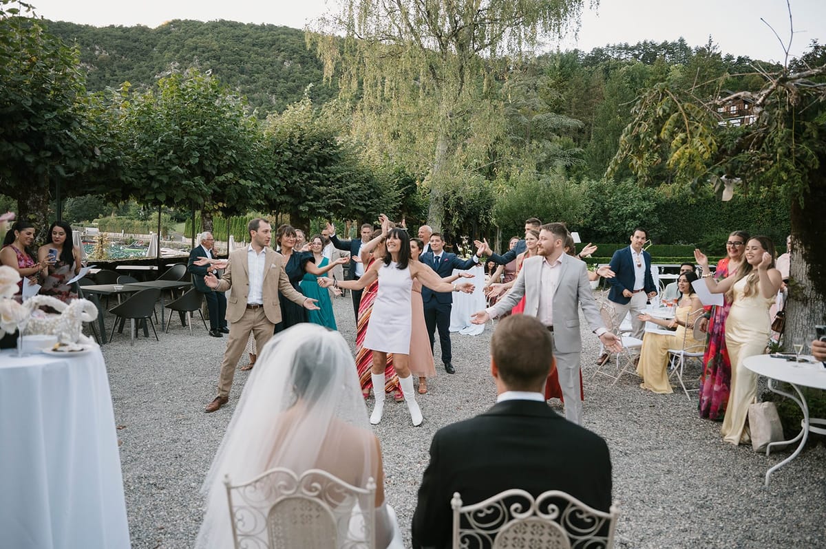 Guests perform a choreographed dance for the seated couple in the garden at Abbaye de Talloires