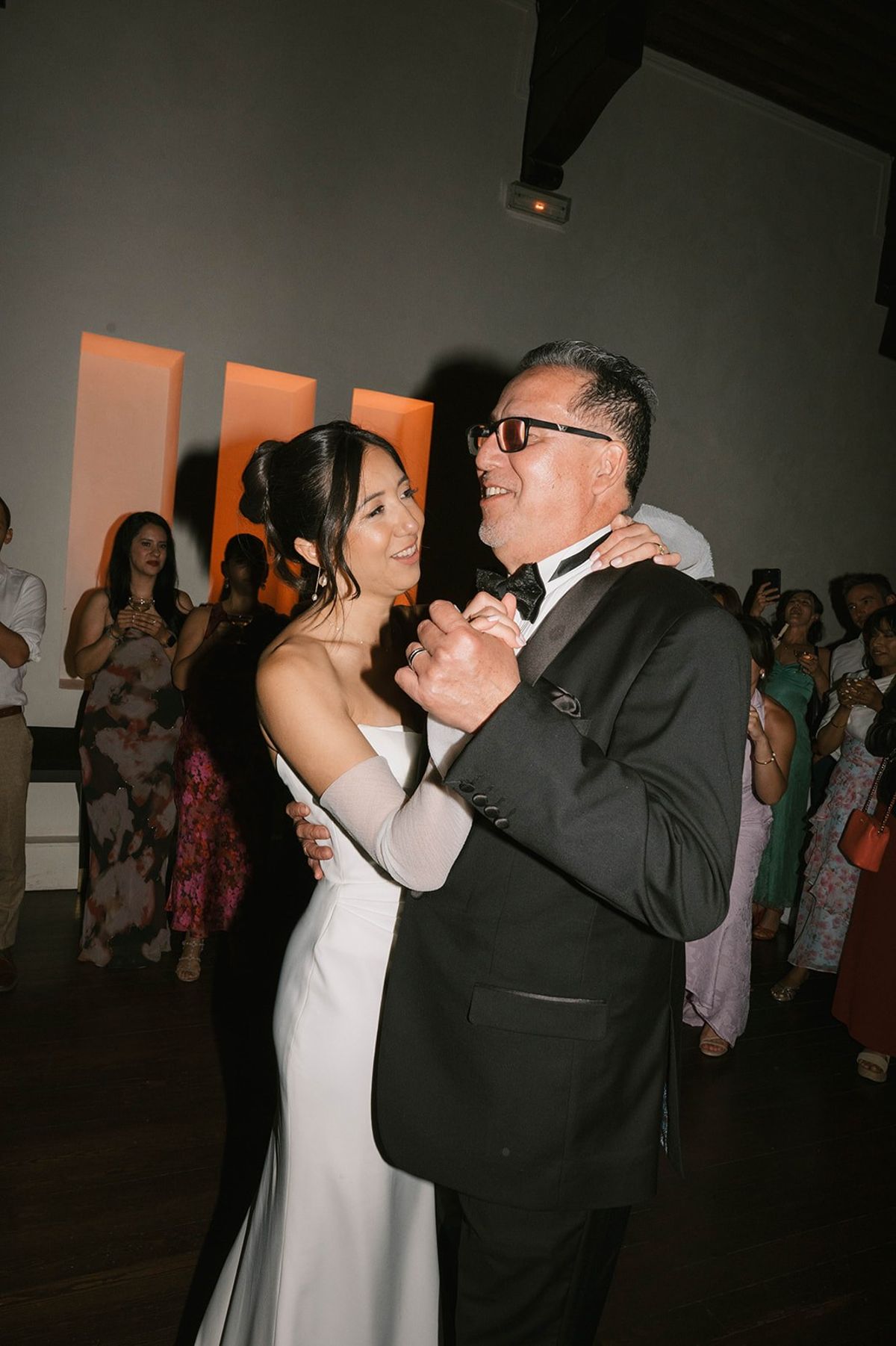 Bride dances with her father under amber stage lighting at Abbaye de Talloires