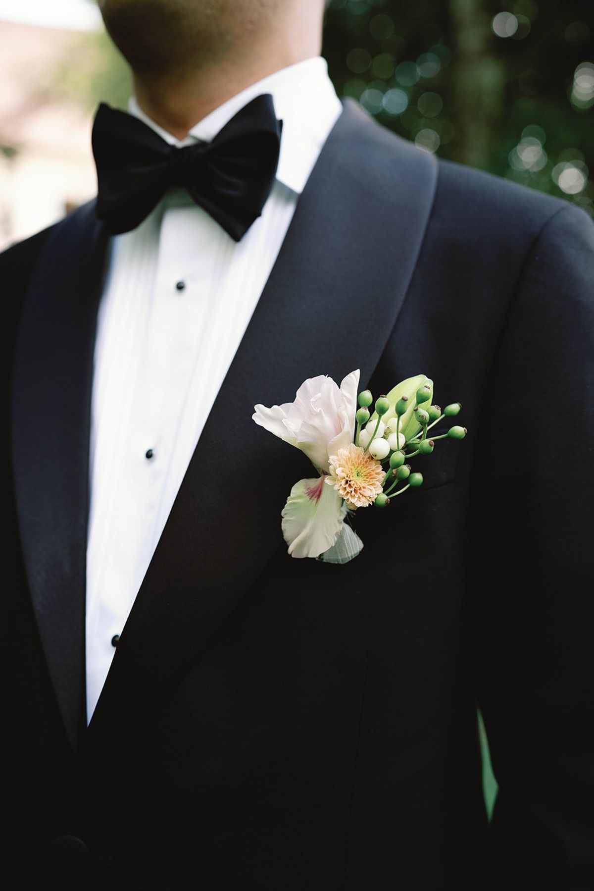 Close up of the groom's orchid and peach dahlia boutonniere at Abbaye de Talloires