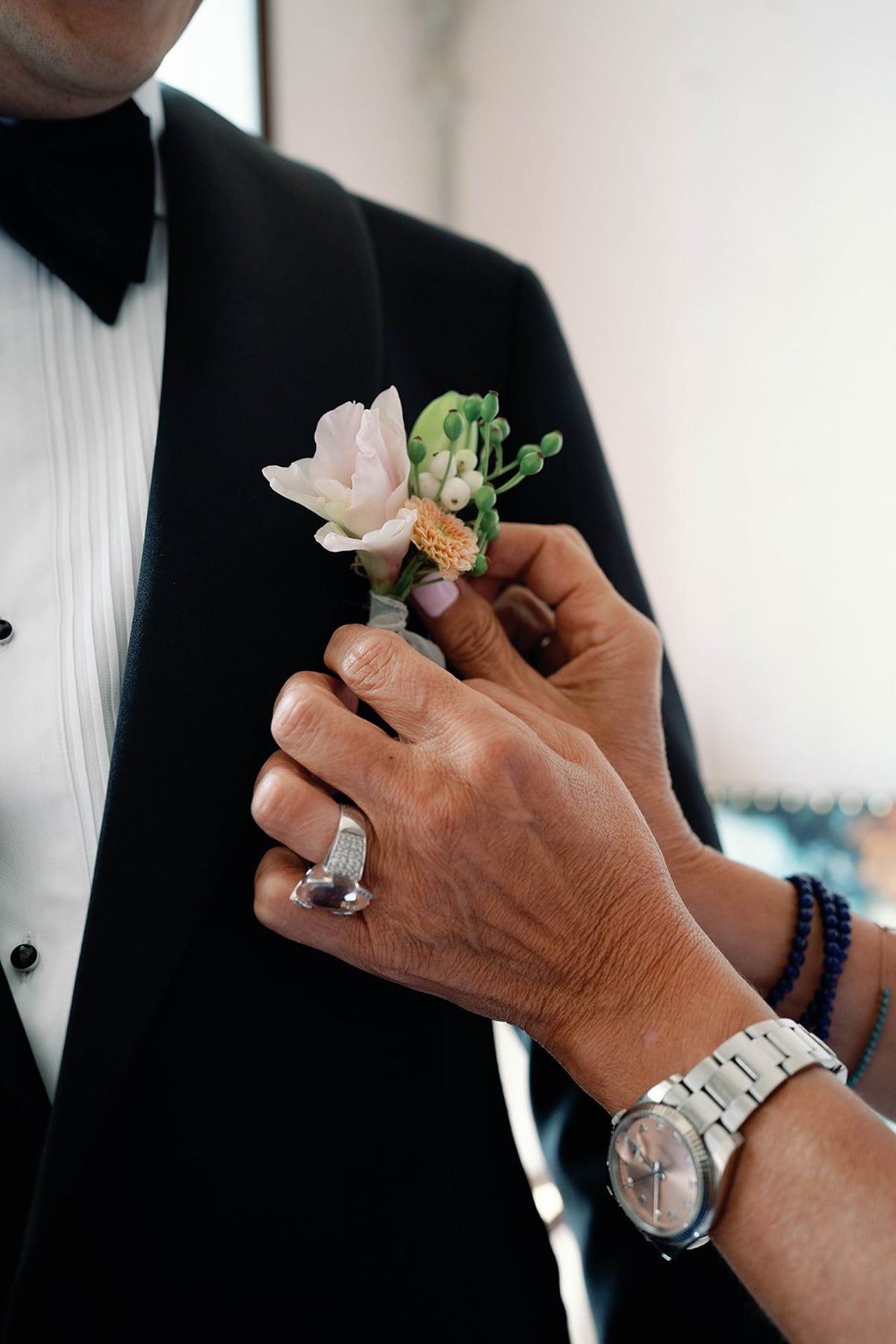 Mother of the groom pins a blush boutonniere onto the tuxedo at Abbaye de Talloires