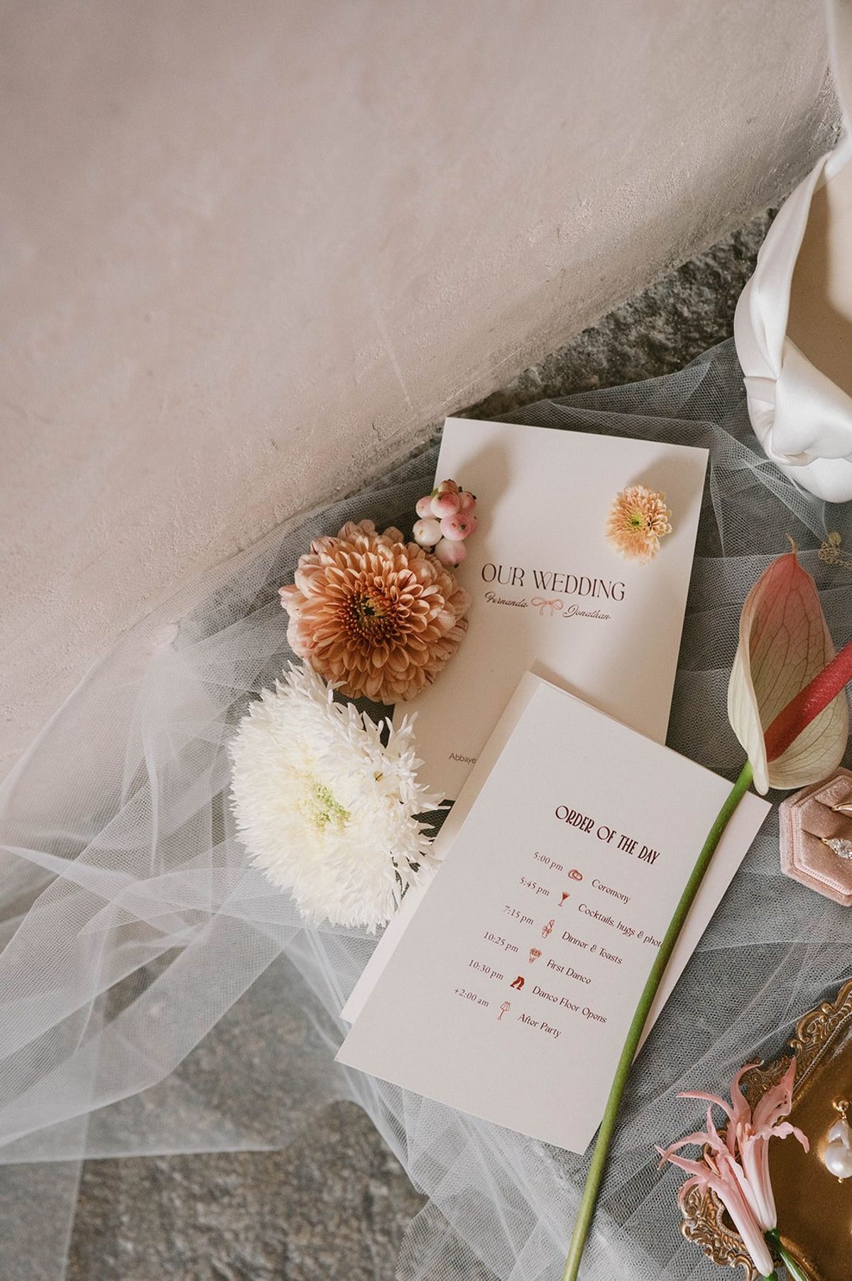 Order of the day card flat lay with dahlias and anthurium on tulle veil at Abbaye de Talloires