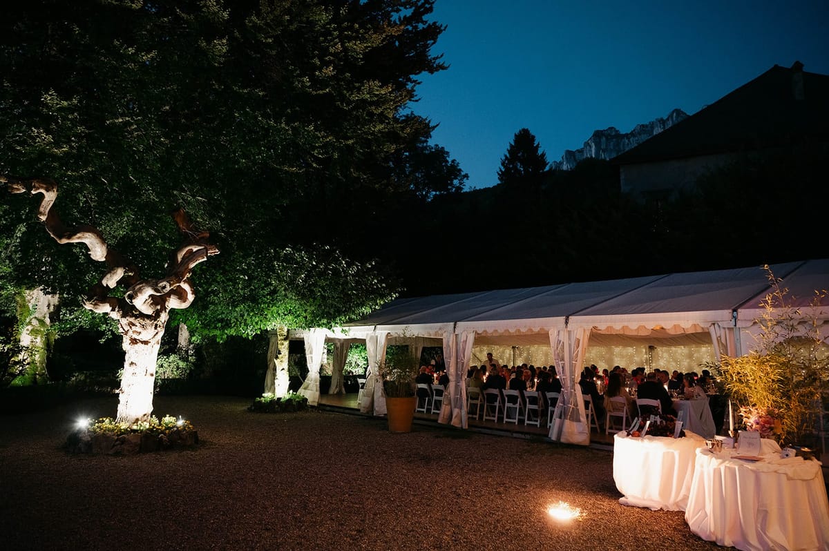 Glowing marquee dinner with Alpine peaks at twilight at Abbaye de Talloires