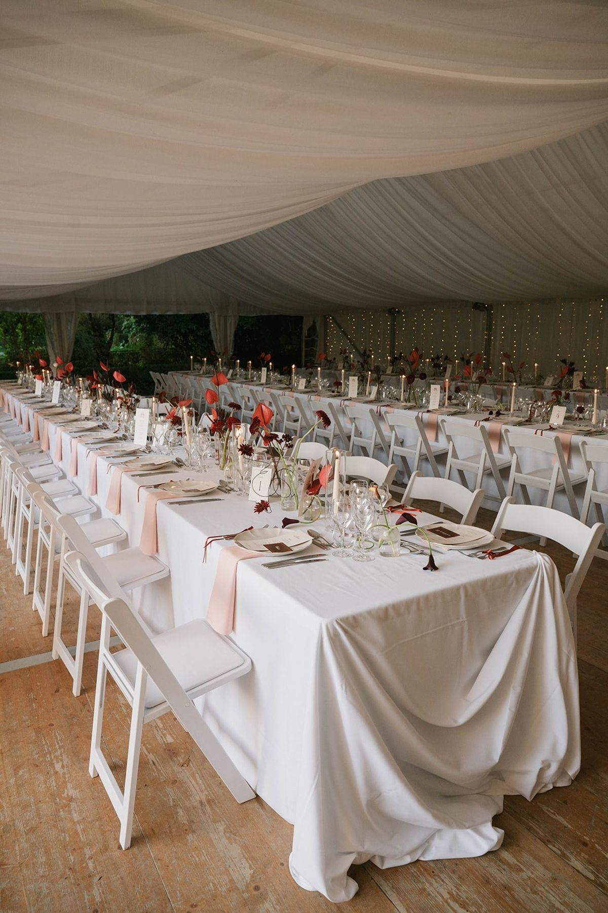 Long banquet tables with red anthurium centrepieces beneath pleated draping at Abbaye de Talloires