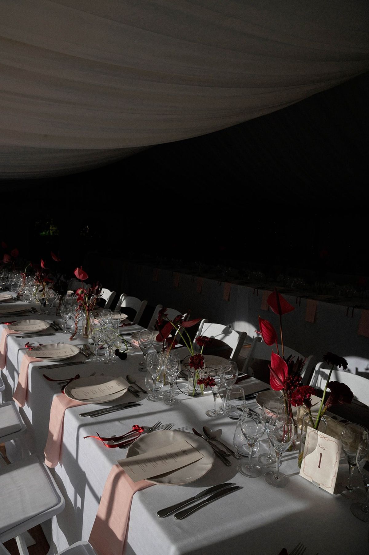 Long table set with red anthurium centrepieces and blush silk napkins at Abbaye de Talloires