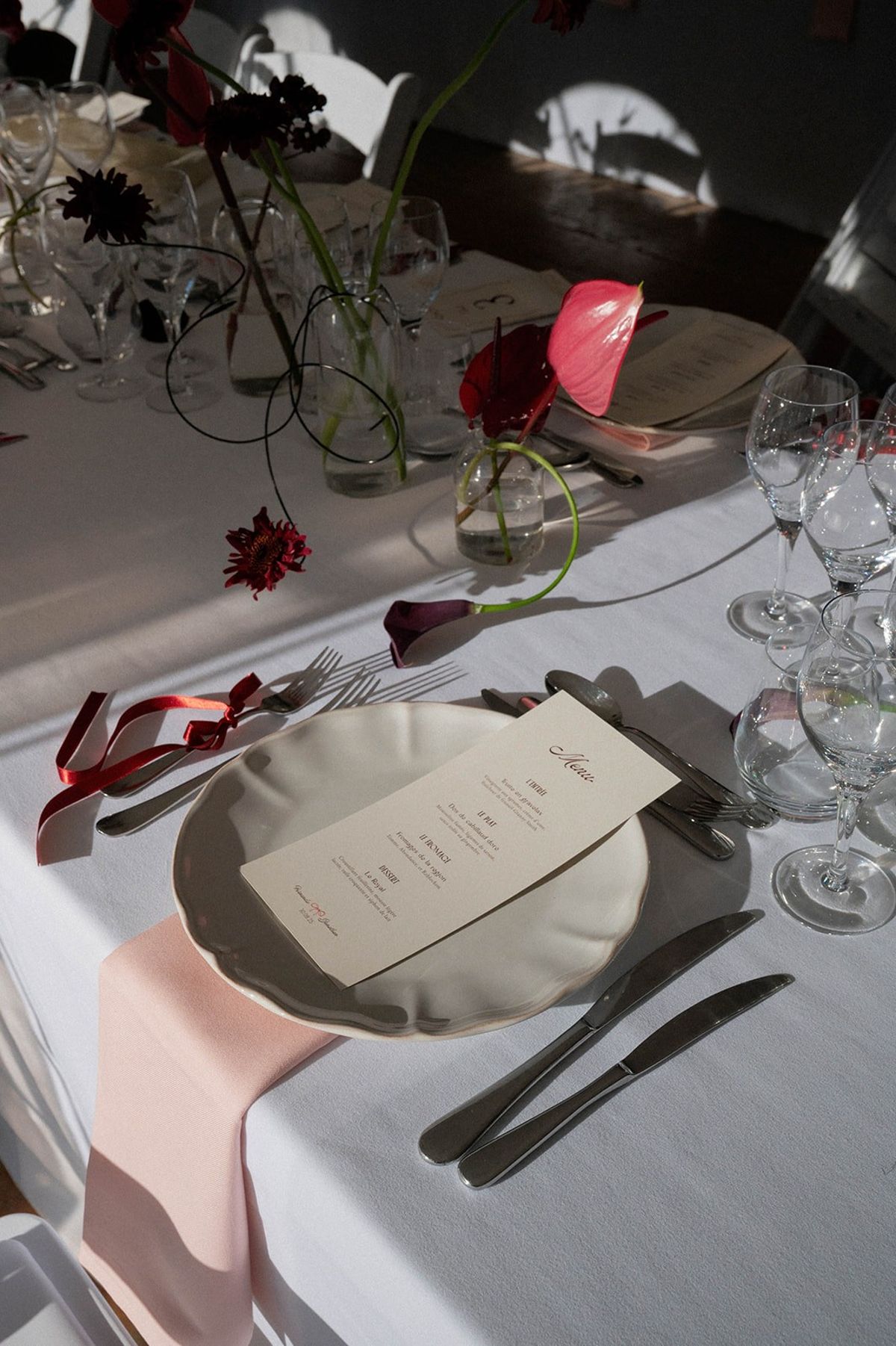 Place setting with menu card and pink anthurium centrepiece at Abbaye de Talloires