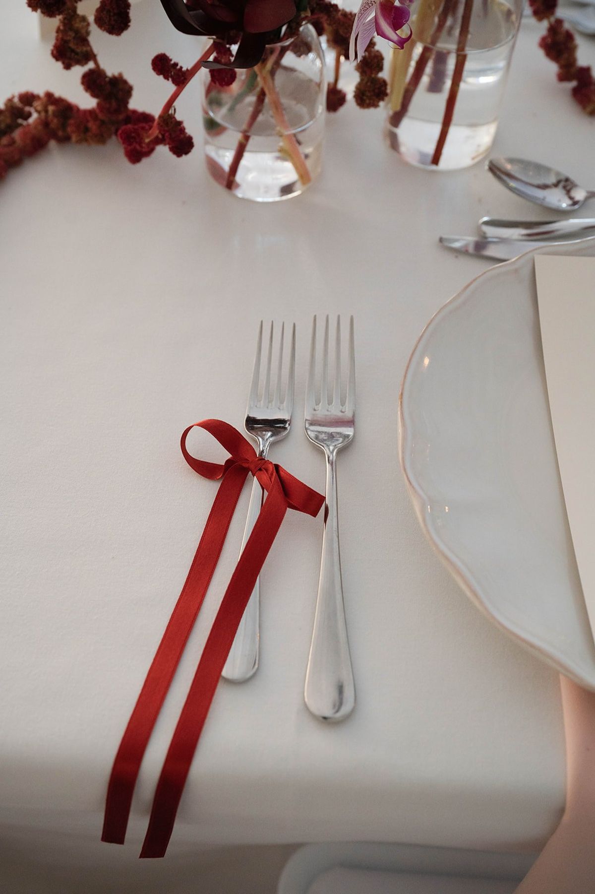 Silver forks tied with a red satin ribbon bow on white linen at Abbaye de Talloires