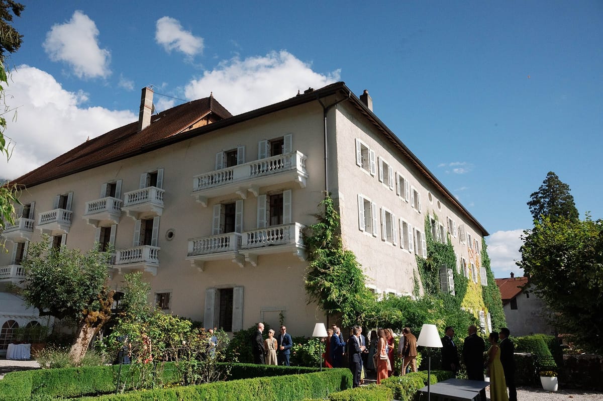 Guests mingle in the formal garden beneath the abbey facade at Abbaye de Talloires